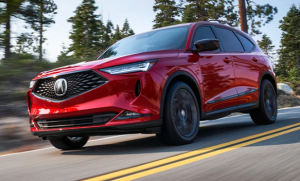 A red 2024 Acura MDX driving down a wooded road near Indianapolis, Indiana