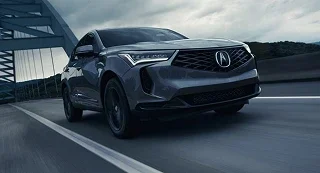 Gray Acura RDX crossing a bridge with its headlights on