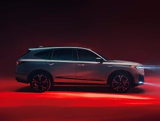 Side profile of an Acura SUV lit by red studio light