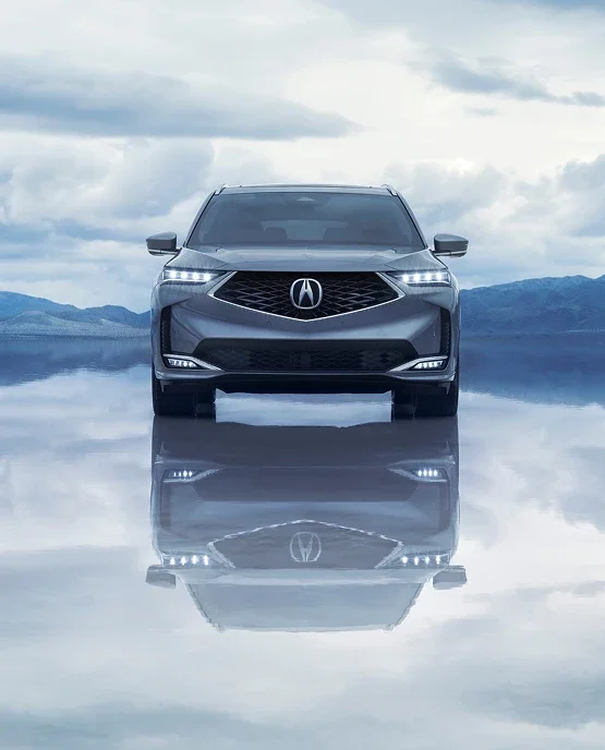Front view of a gray Acura SUV reflected on a mirrored salt flat
