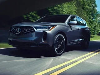 Gray Acura RDX driving on a tree-lined road