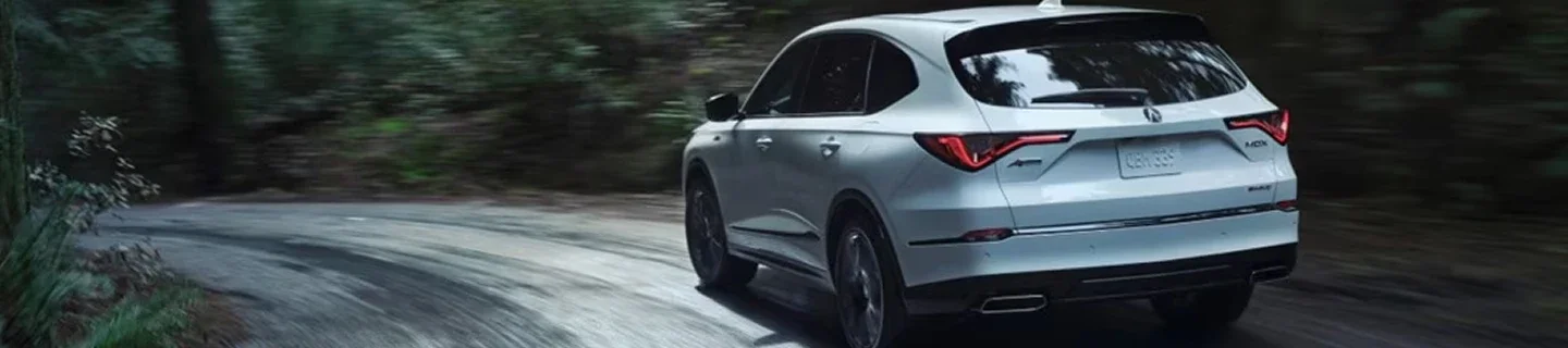 Acura MDX driving away along a tree-lined road