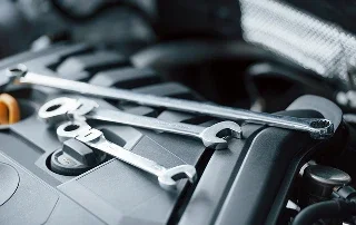 Combination wrenches laid across the engine cover of an Acura in the service bay